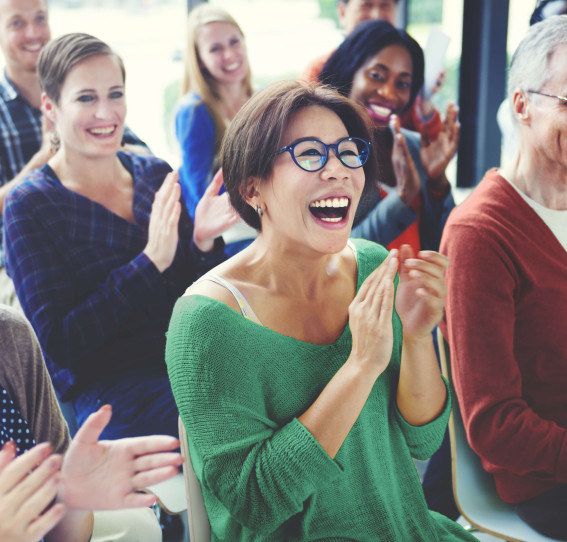 group of people sitting down in causal clothing applauding while laughing and smiling