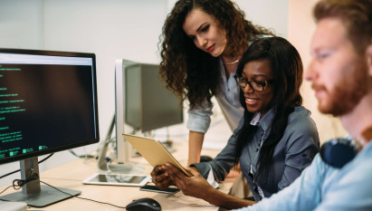 two women working together with man working on computer