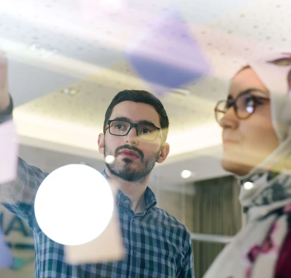 window view of two people discussing the messages observed on the post-it notes