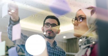 window view of two people discussing the messages observed on the post-it notes