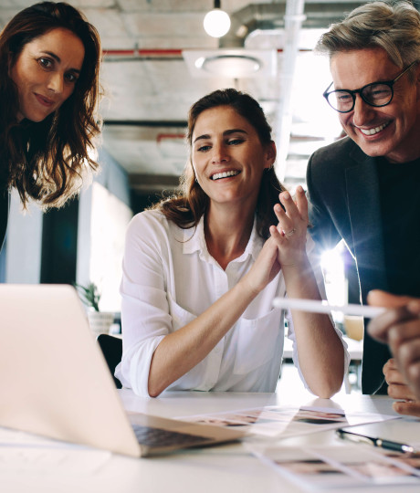 eye level view of four people smiling and wearing smart clothing surrounding laptop