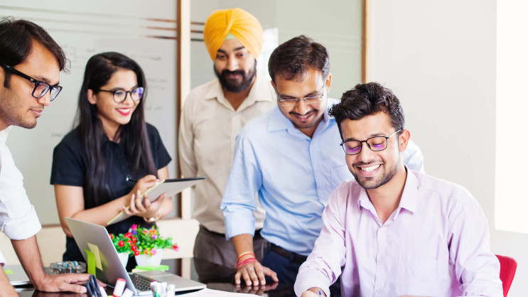 one person smiling and writing on paper with onlookers smiling