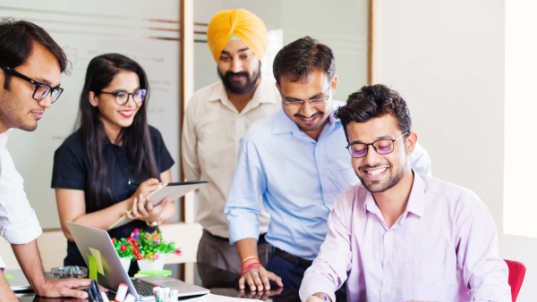 one person smiling and writing on paper with onlookers smiling