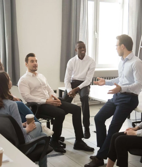 gathering of seven people wearing smart clothing talking in office