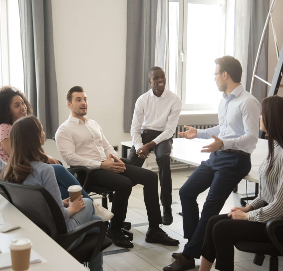 gathering of seven people wearing smart clothing talking in office