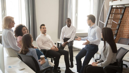 gathering of seven people wearing smart clothing talking in office
