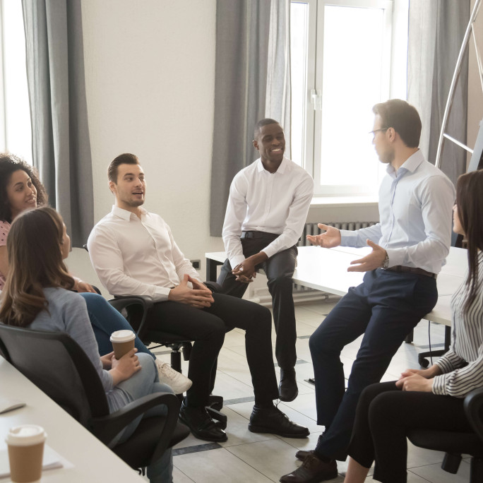 gathering of seven people wearing smart clothing talking in office