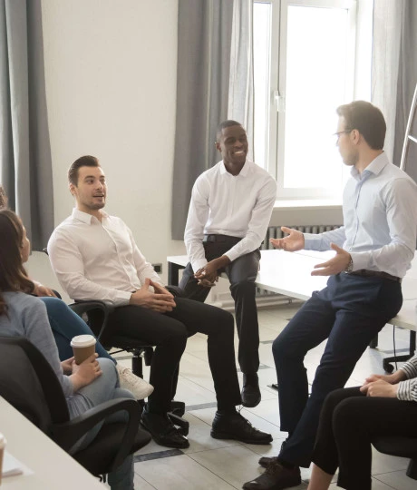 gathering of seven people wearing smart clothing talking in office