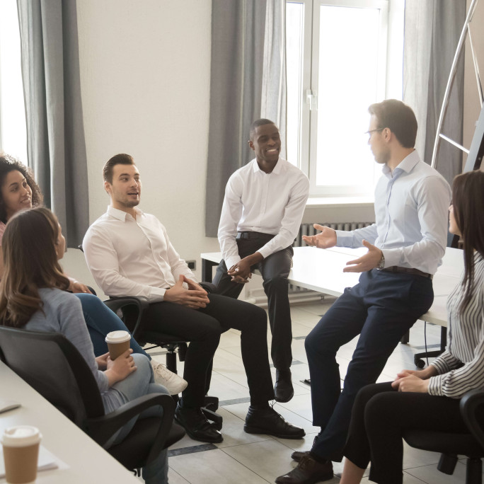 gathering of seven people wearing smart clothing talking in office