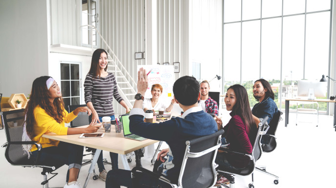 seven people smiling at meeting table with a man's arm raised