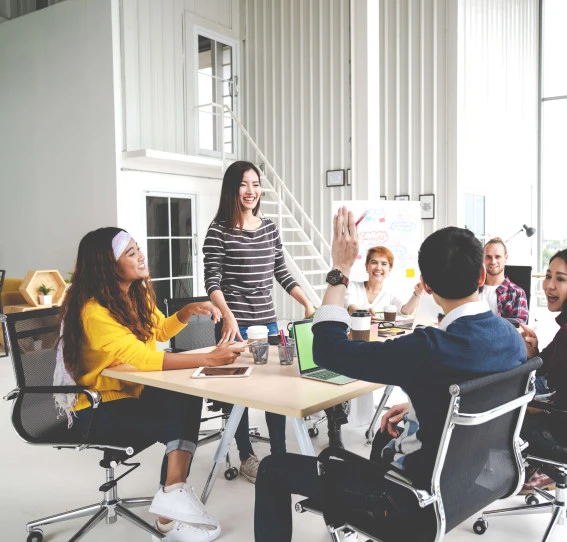 seven people smiling at meeting table with a man's arm raised