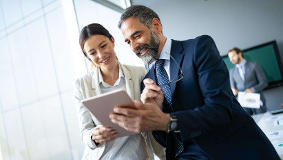 two people smiling while looking at tablet device