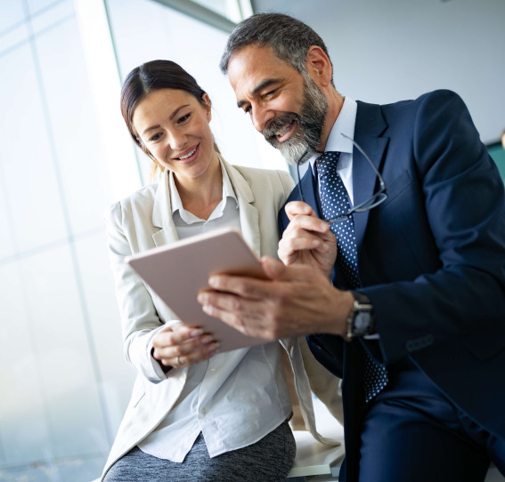 two people smiling while looking at tablet device