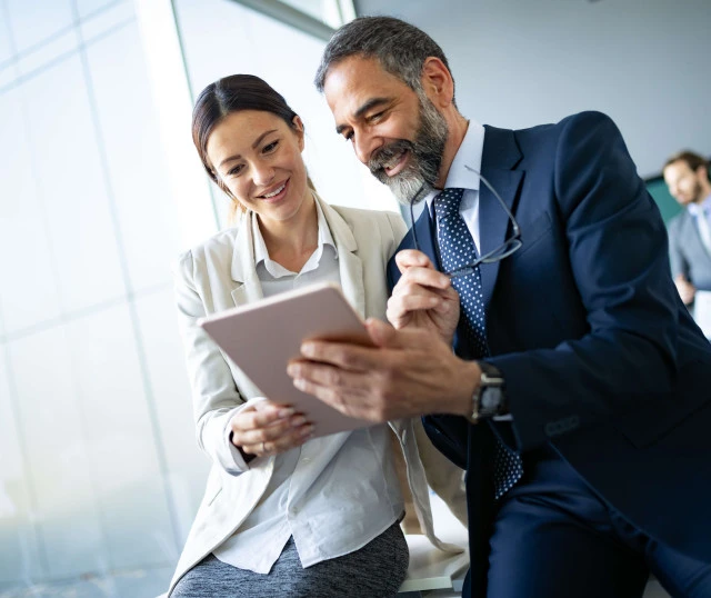 two people smiling while looking at tablet device