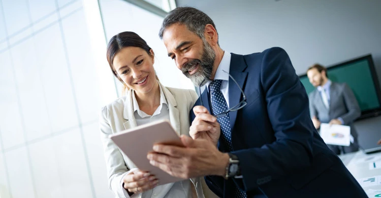 two people smiling while looking at tablet device