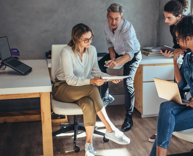 Group of people gathered around a document, all focused and engaged.