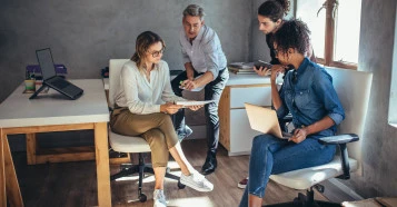 Group of people gathered around a document, all focused and engaged.