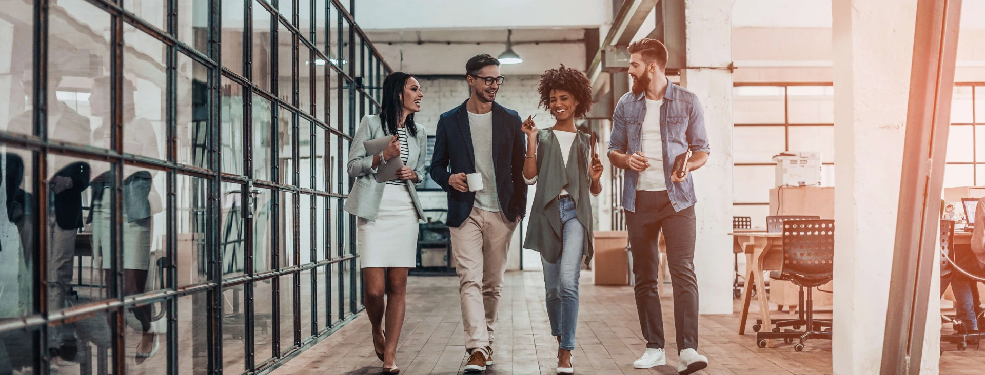 four people walking through office smiling and talking