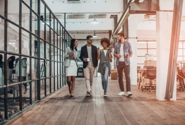 four people walking through office smiling and talking
