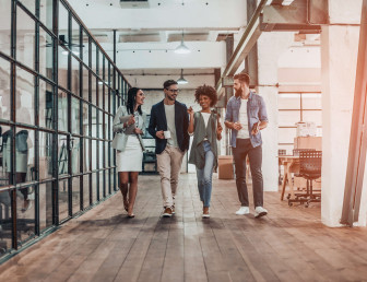four people walking through office smiling and talking