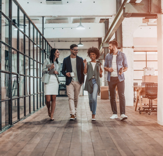 four people walking through office smiling and talking