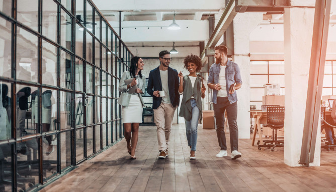 four people walking through office smiling and talking