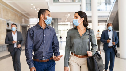 two people walking and talking with masks on with two people in background with masks on