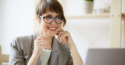 eye level view of woman sitting in front of laptop with headphones in smiling