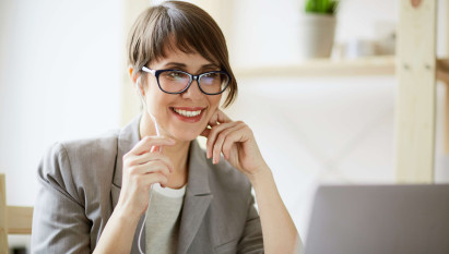 eye level view of woman sitting in front of laptop with headphones in smiling