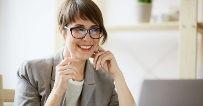eye level view of woman sitting in front of laptop with headphones in smiling