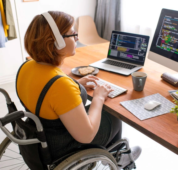 woman sitting in wheelchair with headphones on working on computer