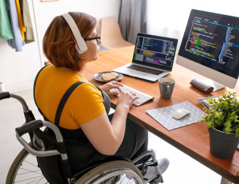 woman sitting in wheelchair with headphones on working on computer