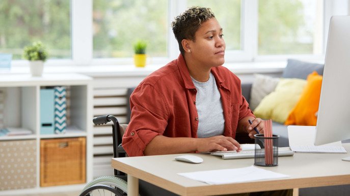 woman in a wheelchair wearing casual clothes working at a desk at home