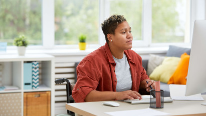 woman in a wheelchair wearing casual clothes working at a desk at home