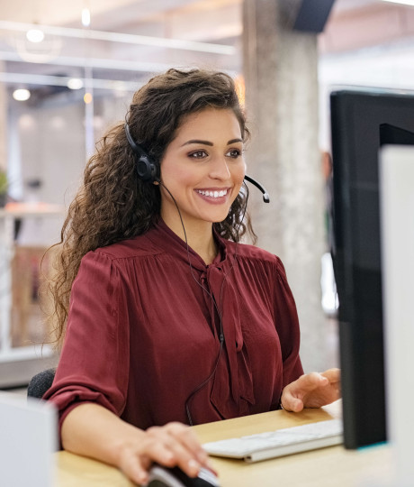 woman smiling sitting at desk with headset on