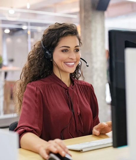 woman smiling sitting at desk with headset on