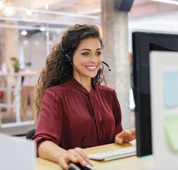 woman smiling sitting at desk with headset on