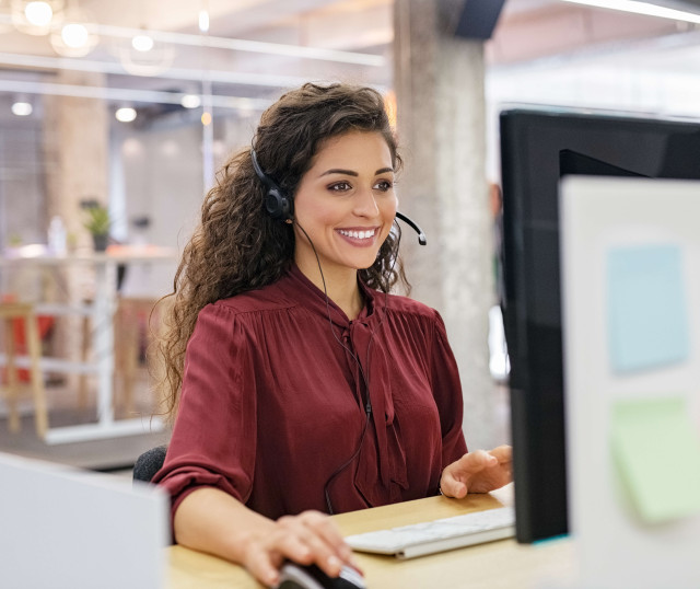 woman smiling sitting at desk with headset on