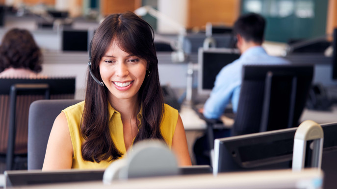 woman in office smiling and sitting at desk with headset on