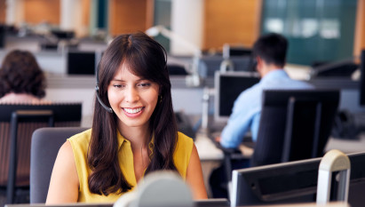 woman in office smiling and sitting at desk with headset on