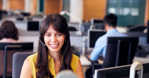 woman in office smiling and sitting at desk with headset on
