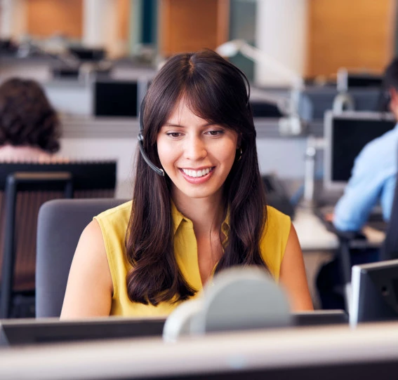 woman in office smiling and sitting at desk with headset on
