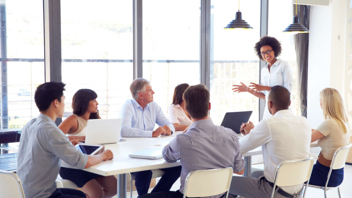 woman leading meeting with seven other people sitting at a table