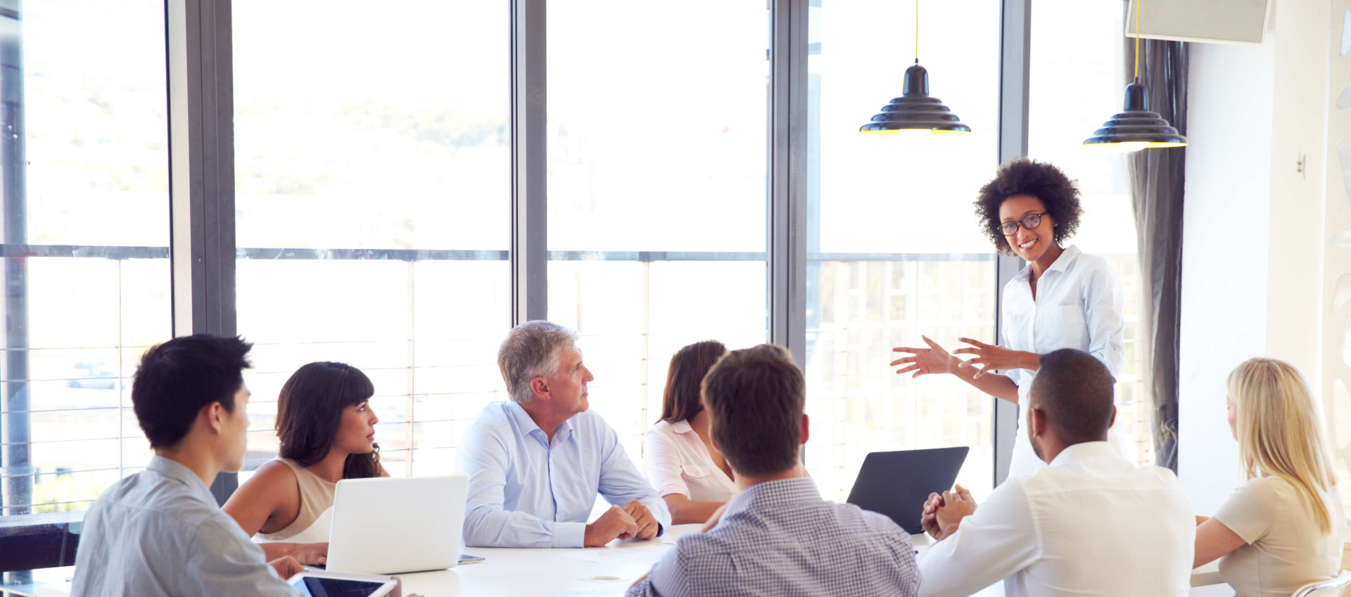 woman leading meeting with seven other people sitting at a table