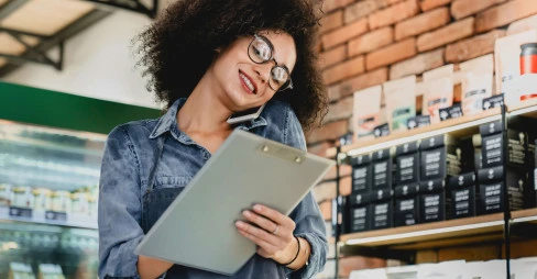 woman on the phone with clipboard in hand smiling in a coffee shop