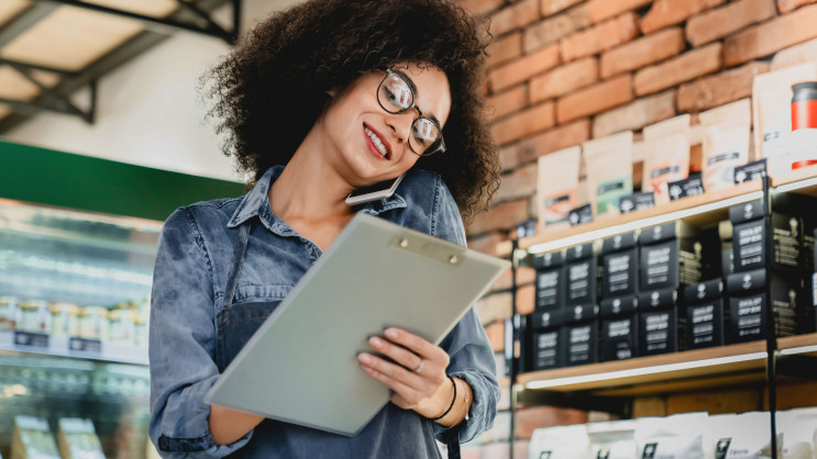 woman on the phone with clipboard in hand smiling in a coffee shop